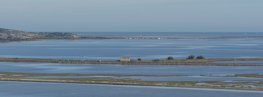 Depuis le pic des Pierres Blanches, au premier plan le tombolo, puis l'étang de la Sèche, la voie ferrée, la maison cantonnière de l'Ardillon et au loin les cabanes de pécheurs de l'Ayrolle